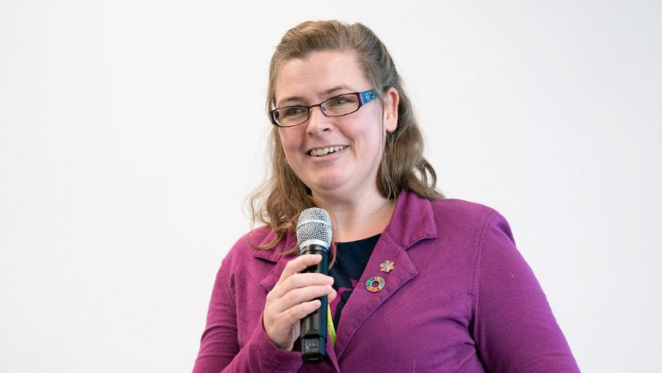 Advisory Board member, Anne, holding a speak, wearing a purple shirt while holding a microphone