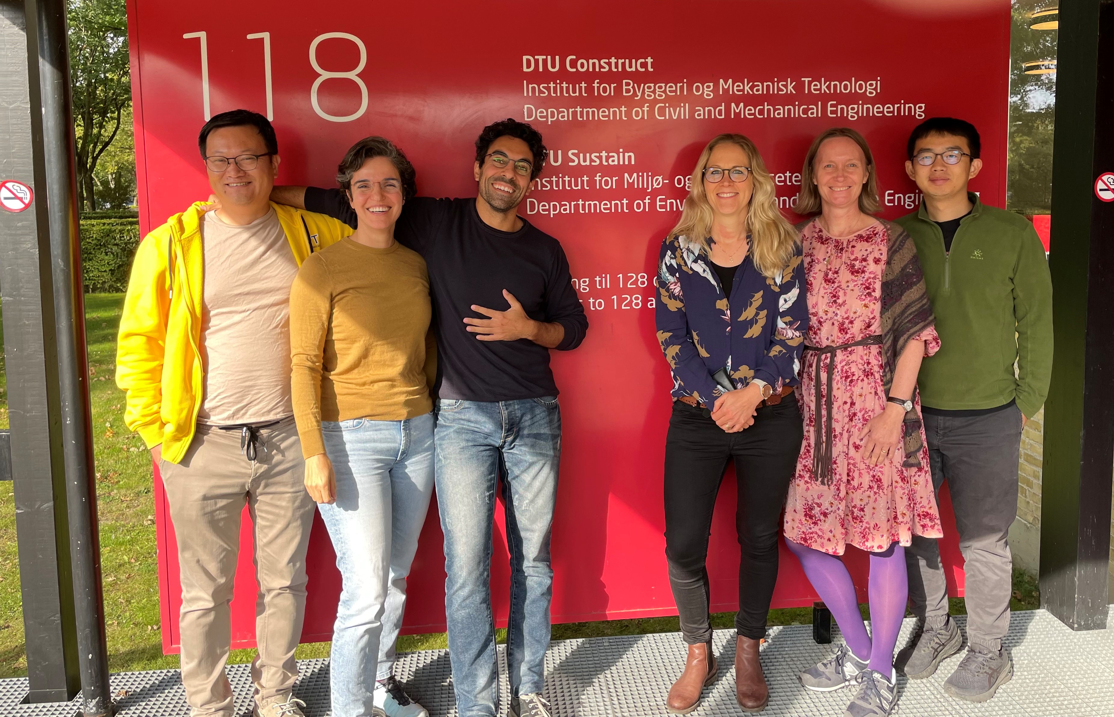 Group photo of project scientists beside a DTU sign with text on it